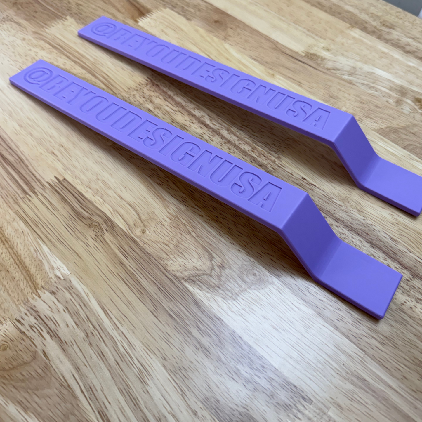 Two purple cameo extender tools with branding on a wood surface