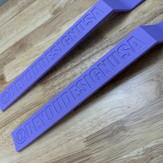 Two purple bands with custom text embossed on them, lying on a wooden surface.
